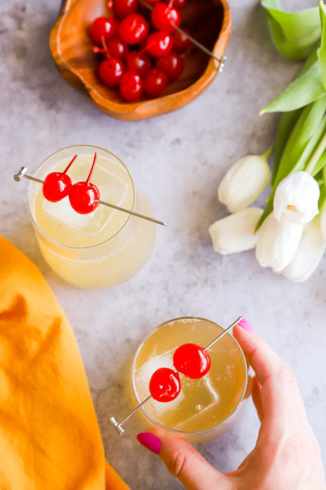 Hand holding cocktail glass with cherry garnish