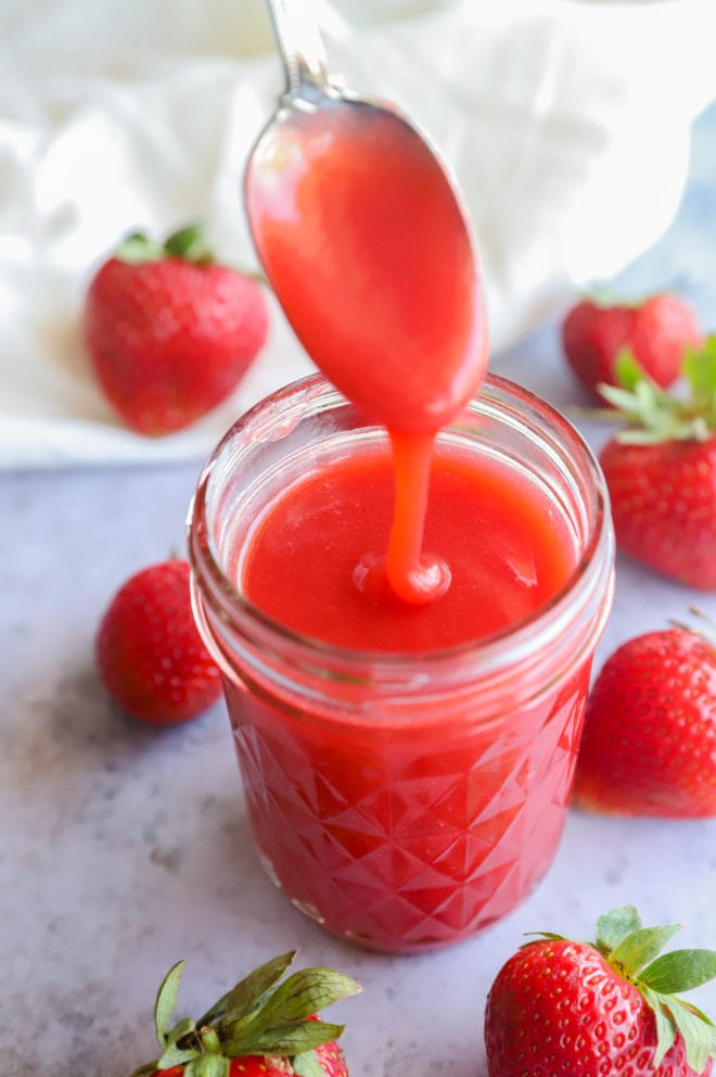 Spoon pouring in sauce for strawberries