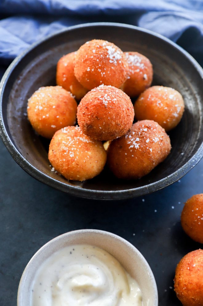 Golden fried balls of cheese with salt on top in a pile in a bowl