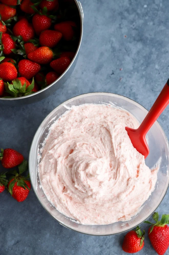 Strawberry buttercream frosting in a bowl with fresh strawberries image