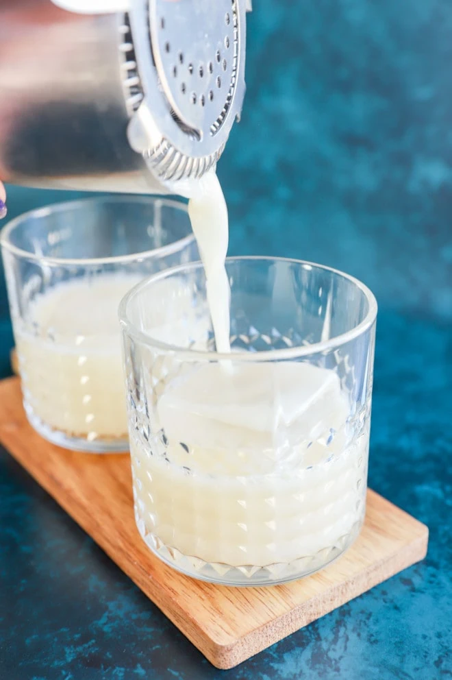 Straining a soju yogurt cocktail into a glass with ice