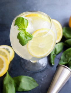 Lemon basil cocktail in a glass with basil and lemon wheel