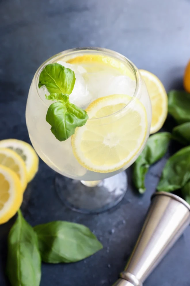 Lemon basil cocktail in a glass with basil and lemon wheel