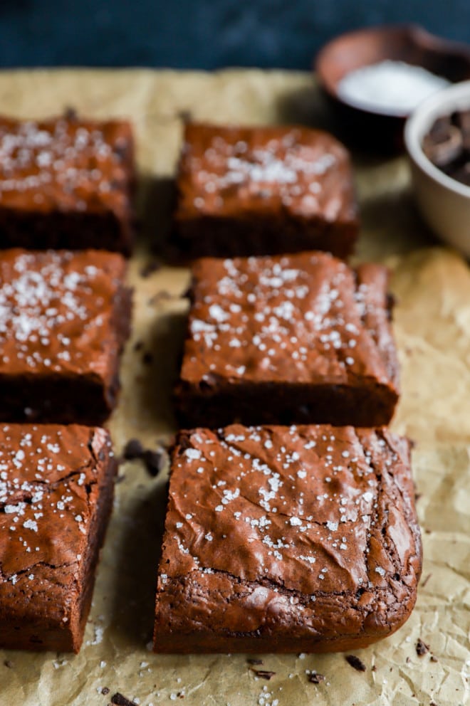 Triple chocolate brownies on parchment paper with salt sprinkled on top