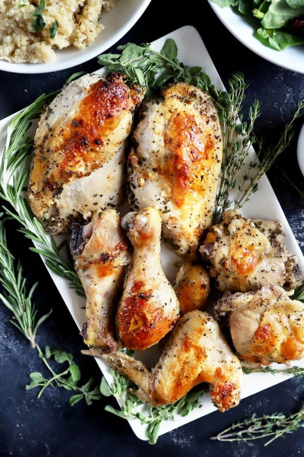 Roasted chicken on a white plate with fresh herbs