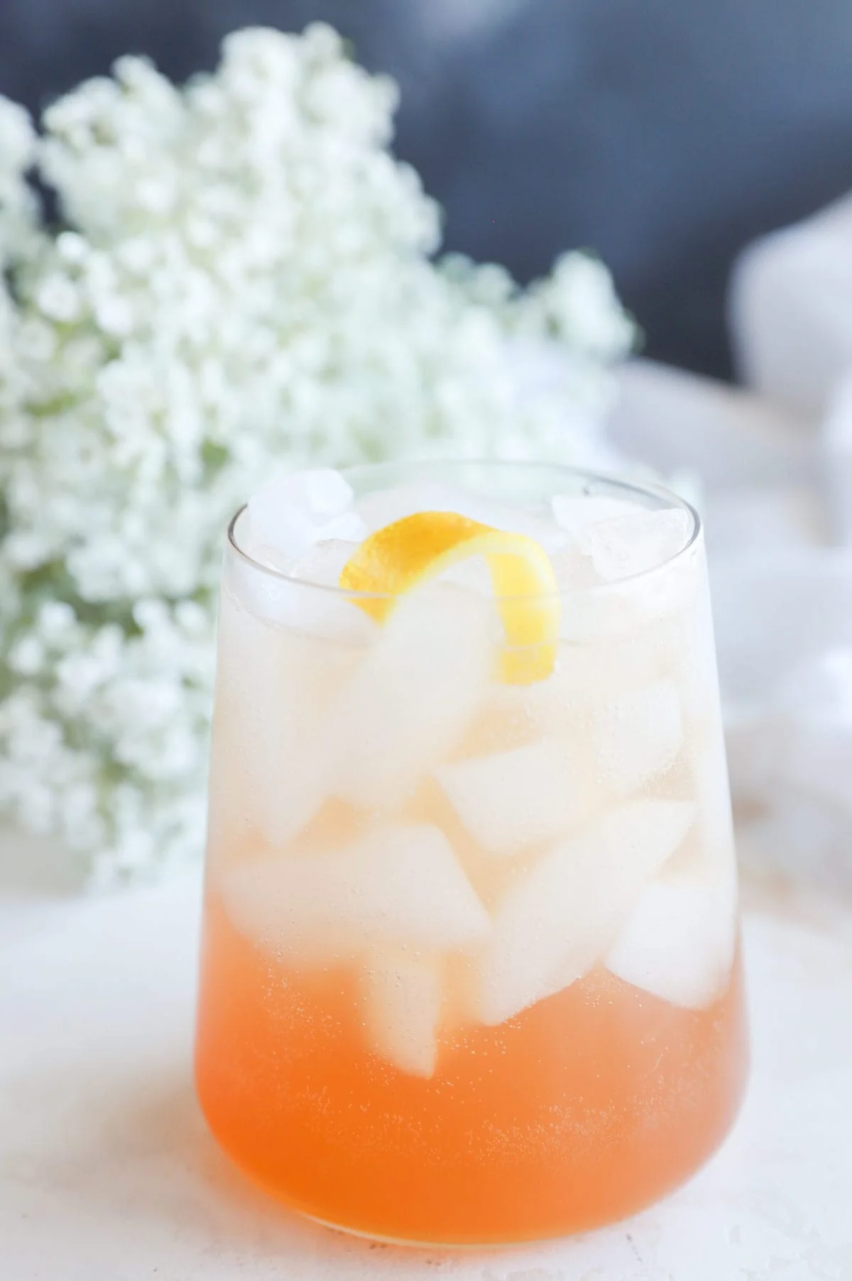 Side photo of a gin cocktail in a glass with flowers