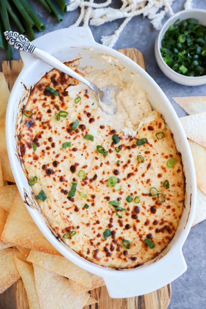 Overhead image of dip in casserole dish with spoon and green onion on top