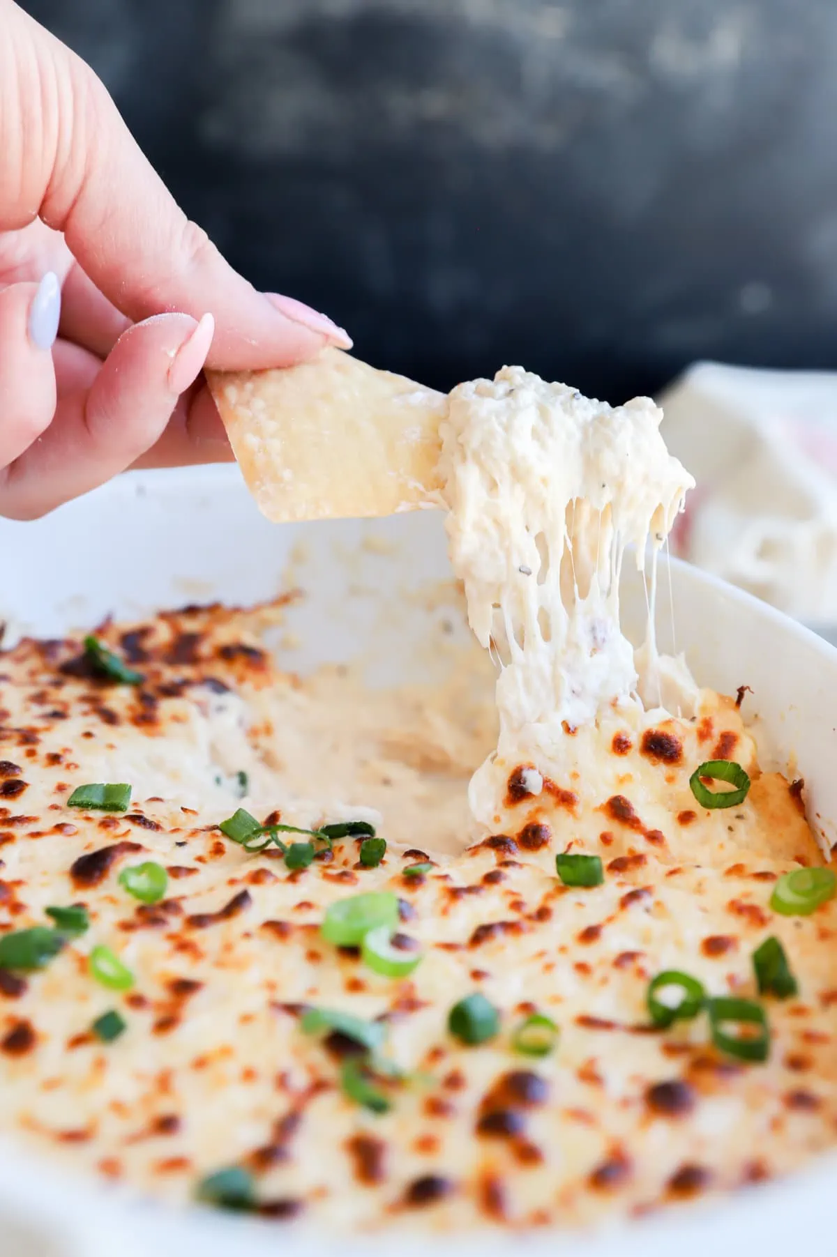 Chip lifting out crab dip from casserole dish image