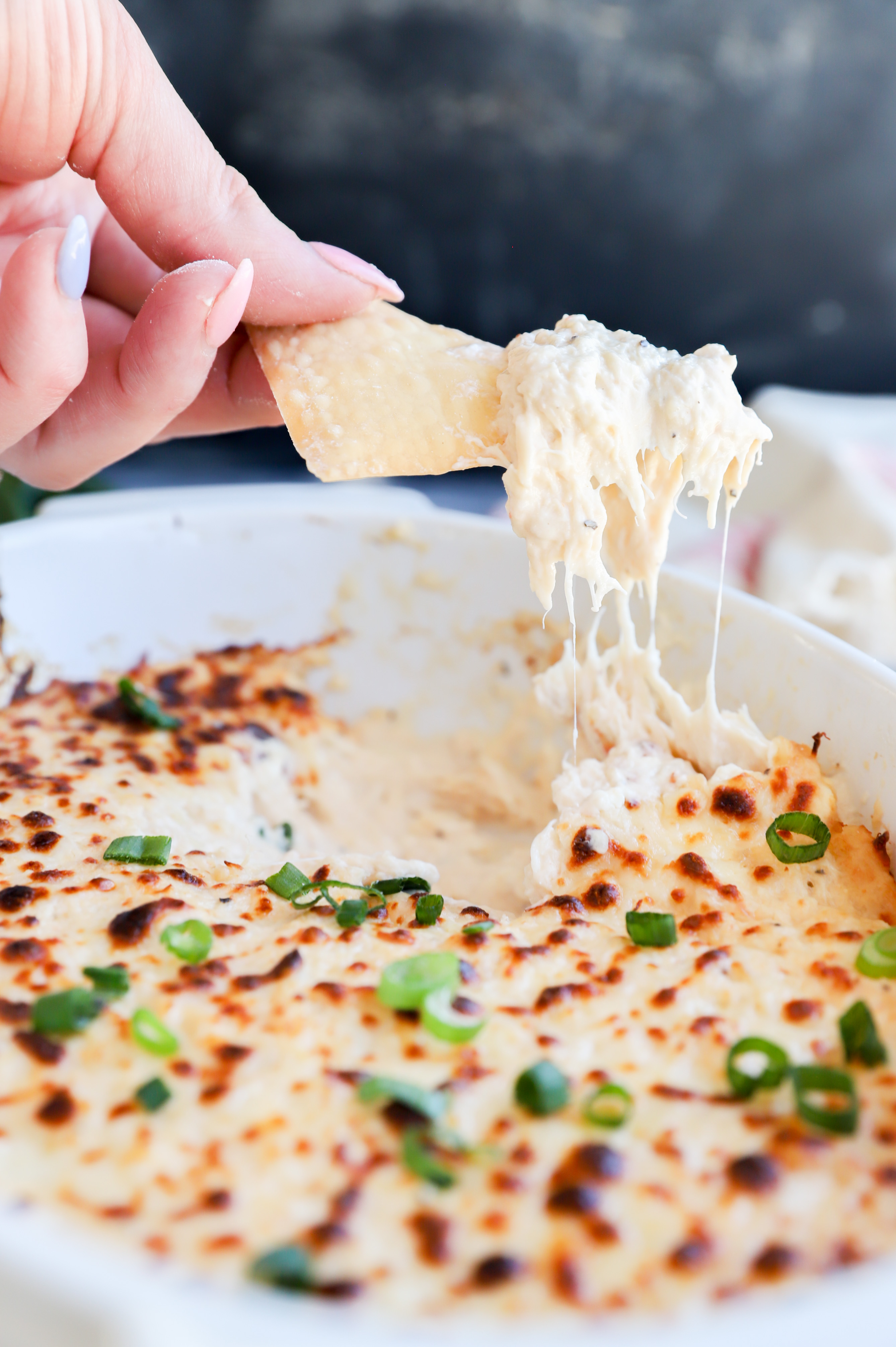 Chip lifting out cheesy dip in casserole dish picture