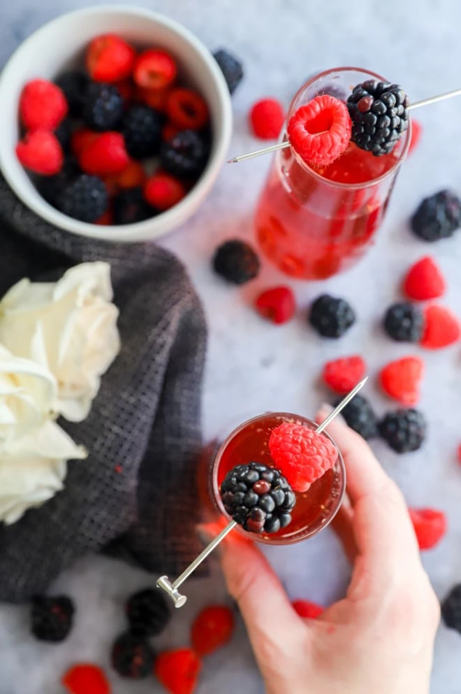 Hand holding champagne glass with berries