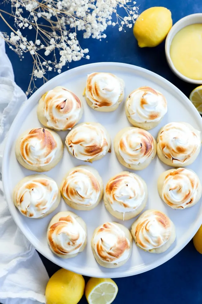 Lemon curd cookies on a cake plate with lemons on the side