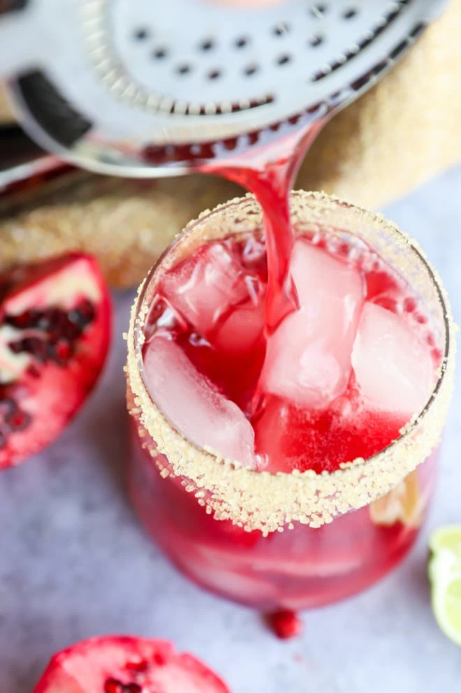 pouring pomegranate margarita into glass image