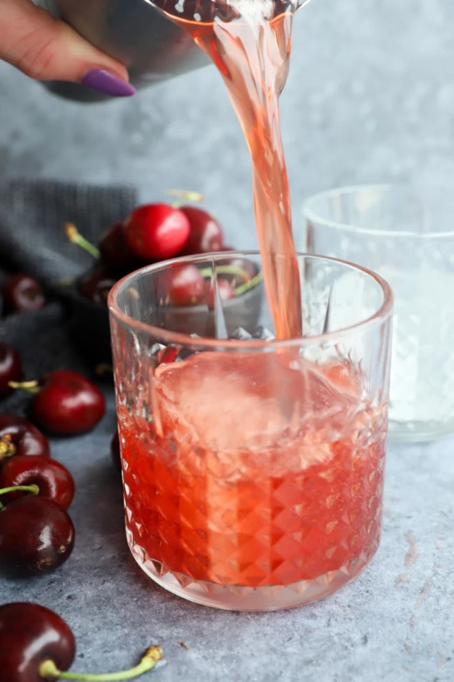 Pouring red summer cocktail into glass image