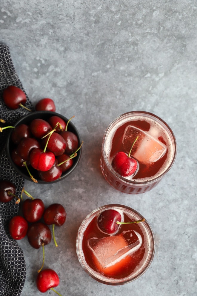 Overhead photo of cocktails in glasses with fresh cherries