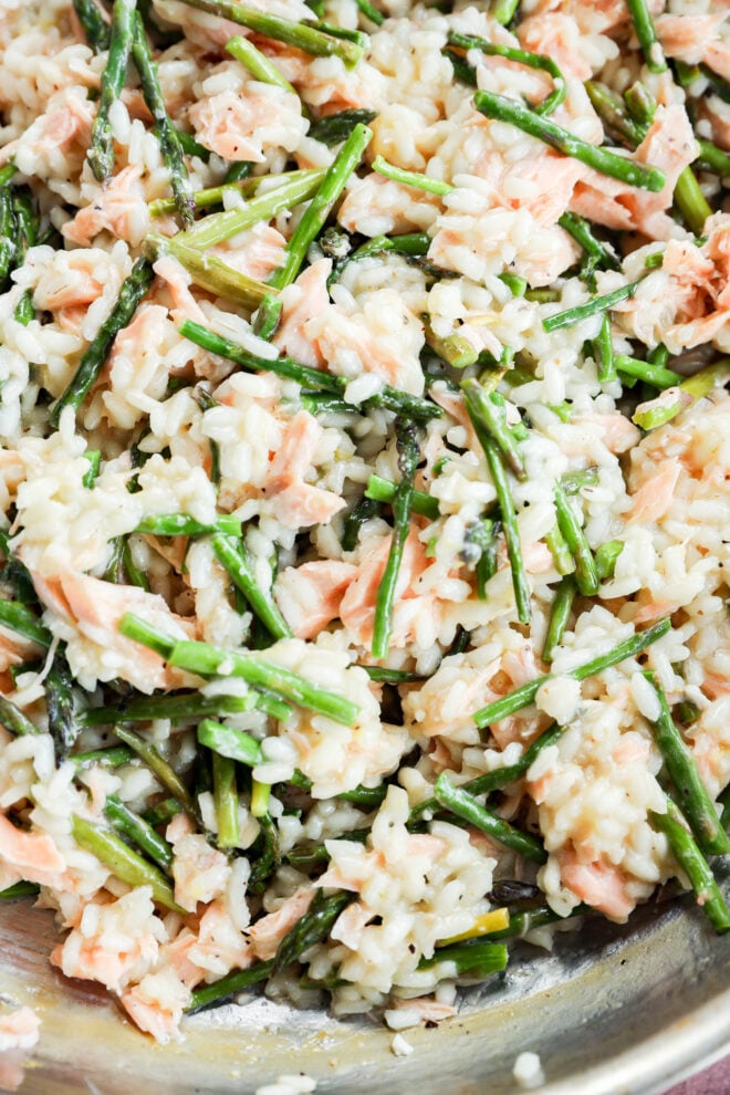 Close-up of creamy Salmon Lemon Risotto with Asparagus, featuring flaky pink salmon pieces and green asparagus spears, all combined in a pan.