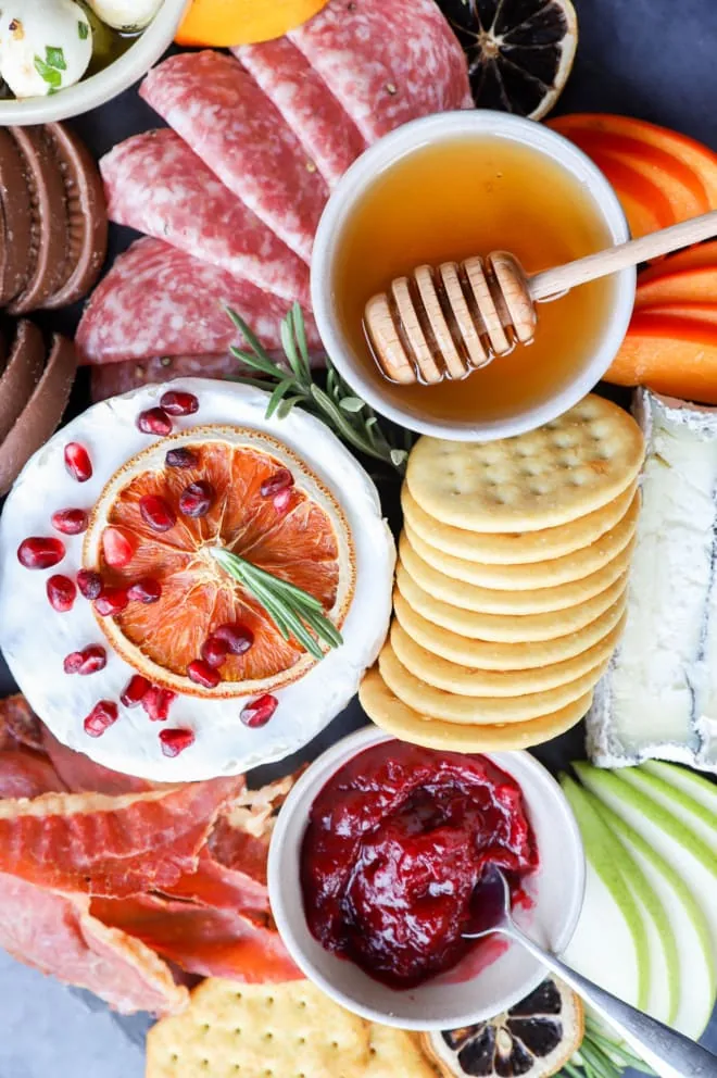 Brie, honey, cranberry jam, and crackers on a platter