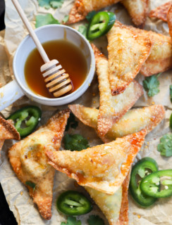 Overhead image of wontons on a baking sheet with hot honey and jalapeños