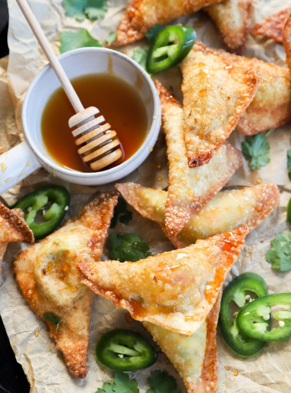 Overhead image of wontons on a baking sheet with hot honey and jalapeños