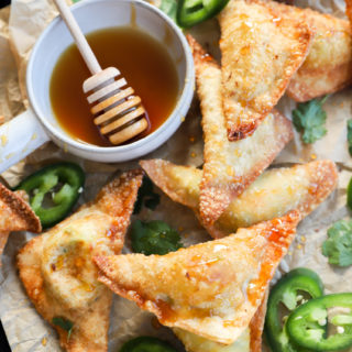 Overhead image of wontons on a baking sheet with hot honey and jalapeños