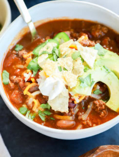 Spicy taco chili in a bowl with avocado, sour cream, and cheese