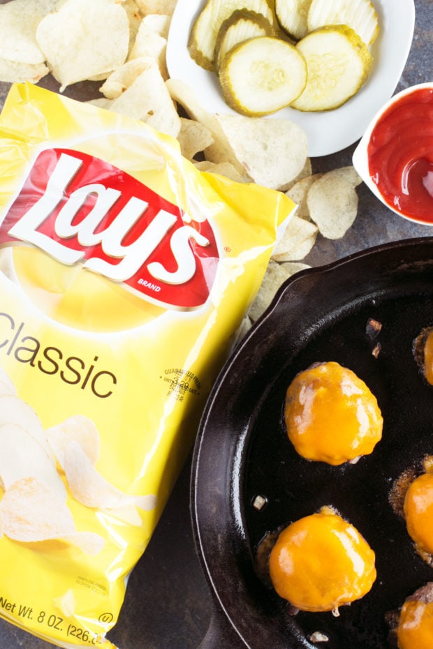 Burgers in pan with chips and pickles overhead photo