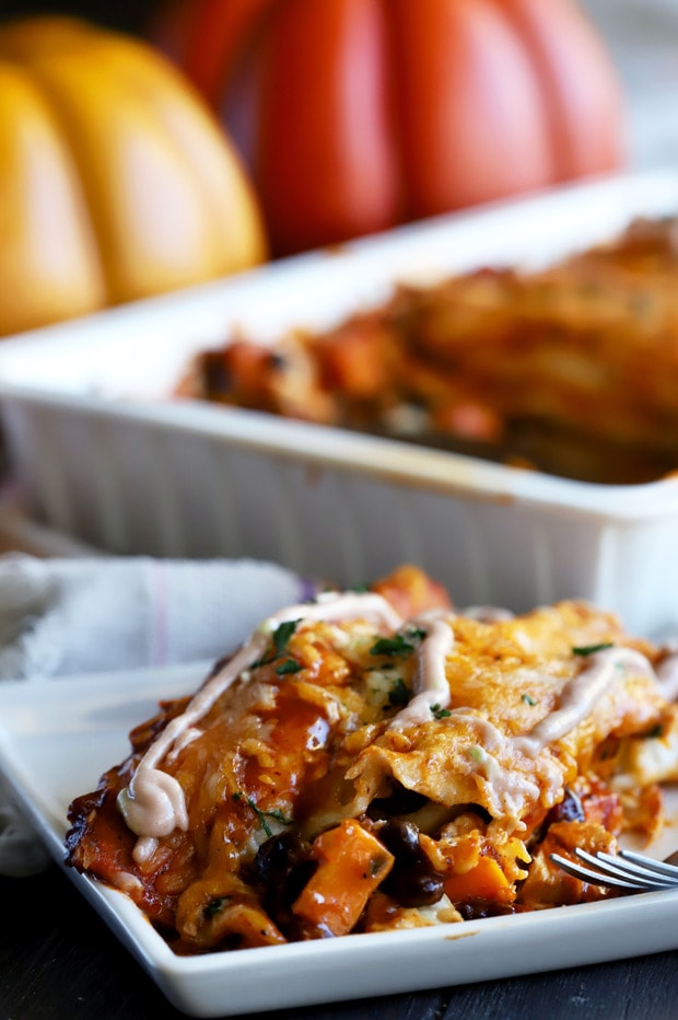 Overhead shot of two enchiladas on a plate with crema and cilantro