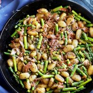 spring brown butter gnocchi in a skillet with asparagus and peas