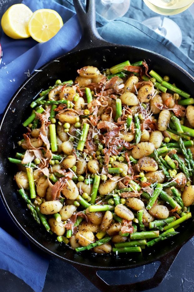 spring brown butter gnocchi in a skillet with asparagus and peas