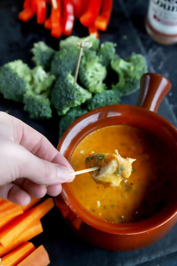 Bread piece being dipped into short rib fondue