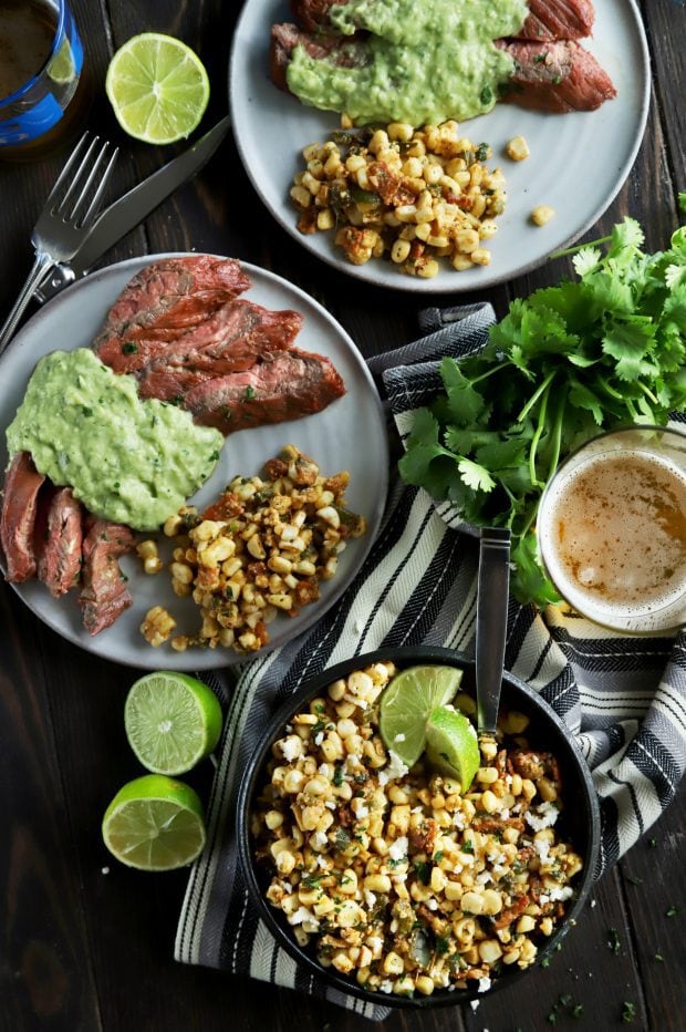 A spread of grilled corn salad with steak and limes