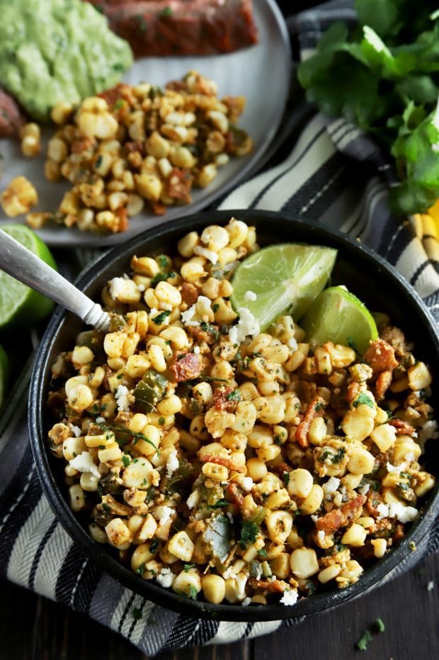 Grilled corn salad in a bowl with limes