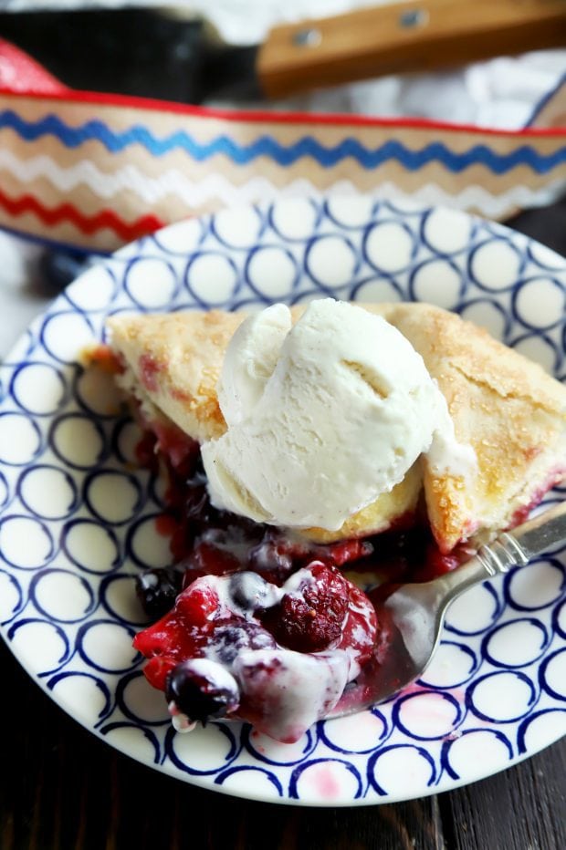 A fork taking a bite for the triple berry galette