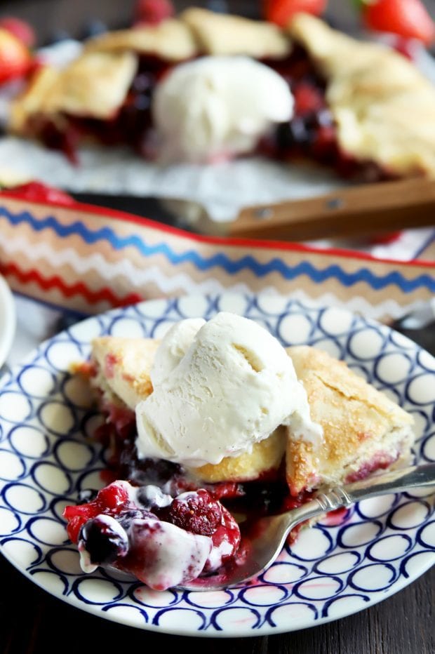 Triple berry galette piece with a fork taking a bite