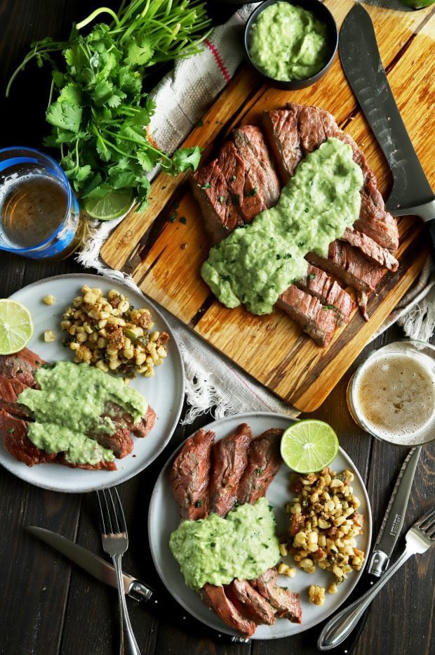 Overhead shot of steak, corn salad, and creamy avocado salsa