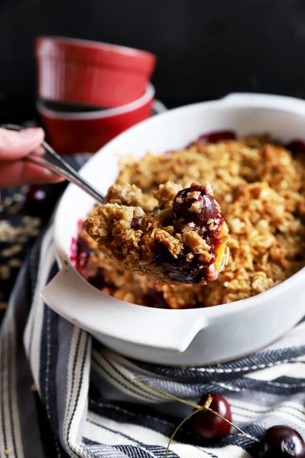 Lifting out a fruit crumble from baking dish