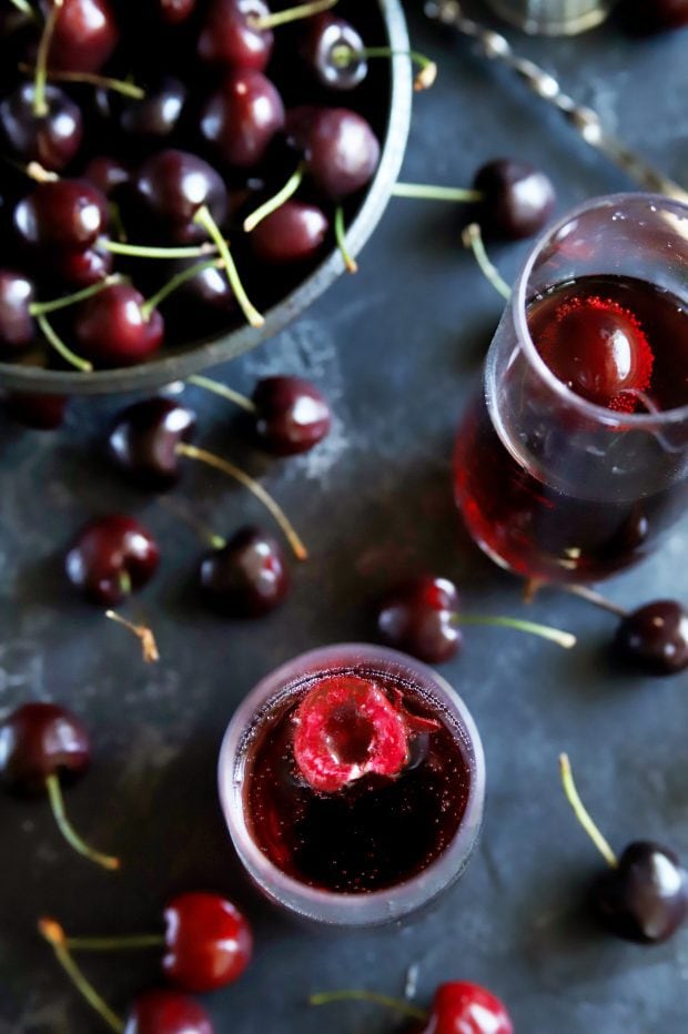 Fresh cherries in a bowl around mimosas in champagne flutes