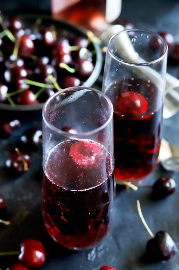 Side shot of champagne flutes with cherry rose mimosas and fresh cherries