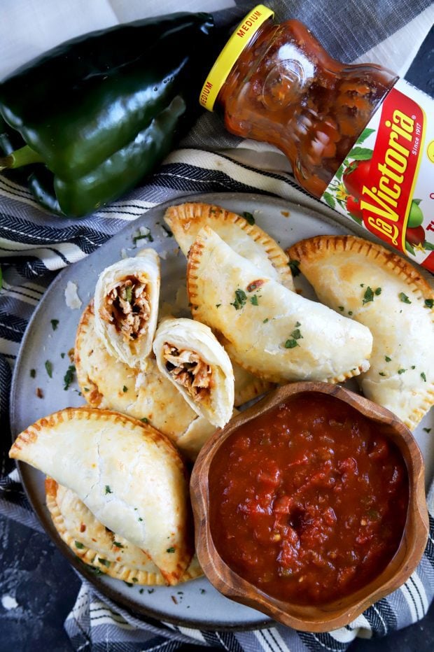 Lots of empanadas with one cut in half and with salsa