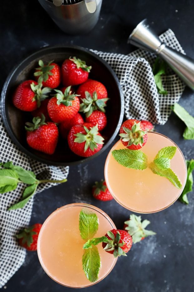 overhead image of vodka gimlets, strawberries, and fresh mint leaves