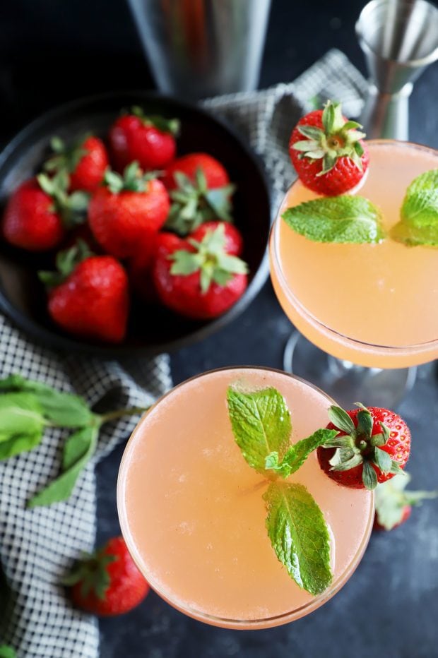 Berries and herbs with vodka for a cocktail in coupe glasses