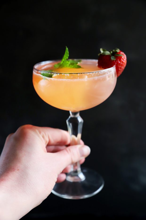 Hand holding a vodka cocktail in a coupe glass