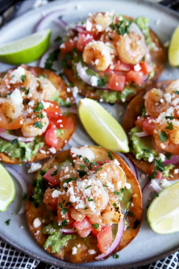 Shrimp tostadas on a plate with limes and pico de gallo