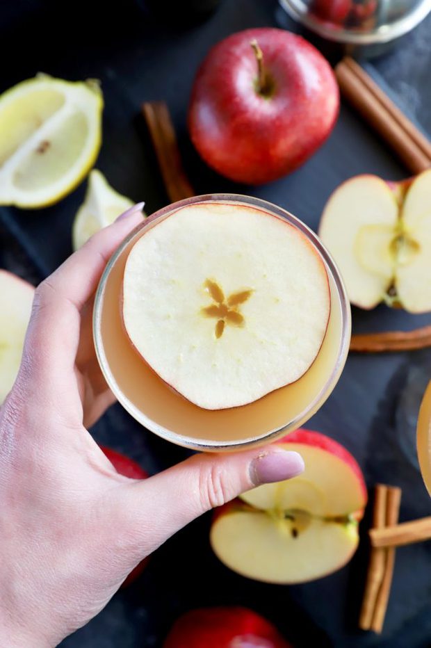 Holding a cocktail glass with whiskey apple drink