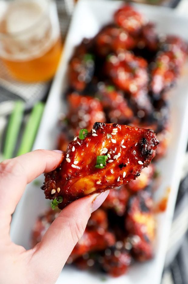 Hand holding a wing with Korean BBQ sauce on it