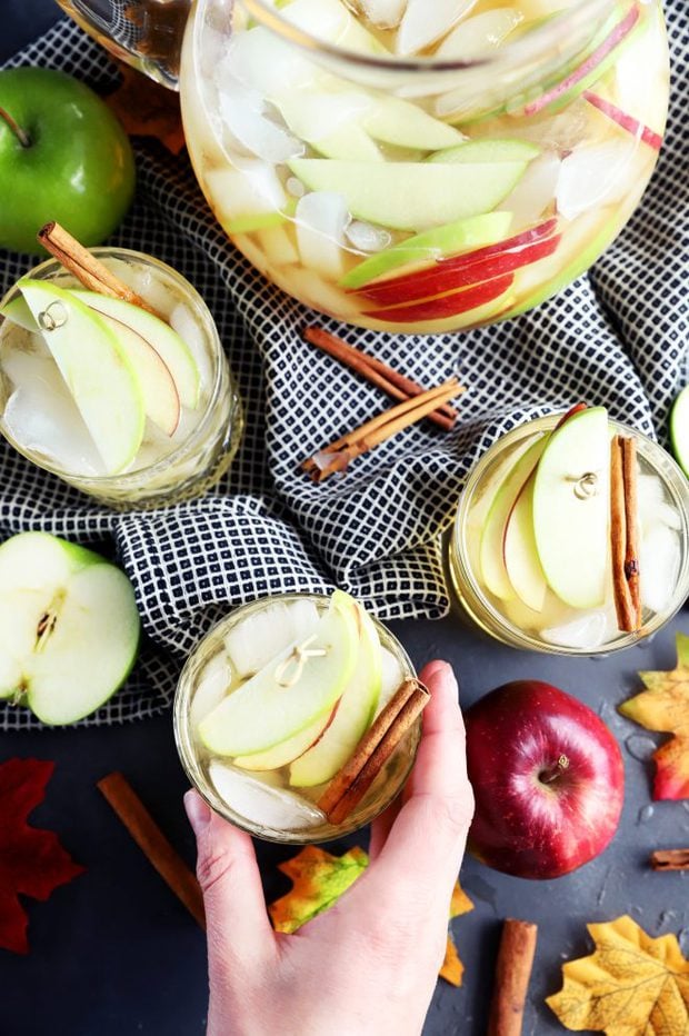 Hand grabbing a glass of white apple pie sangria