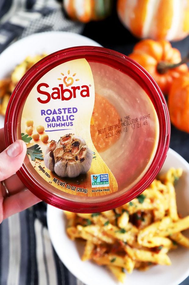 Hand holding a tub of Sabra Roasted Garlic Hummus 