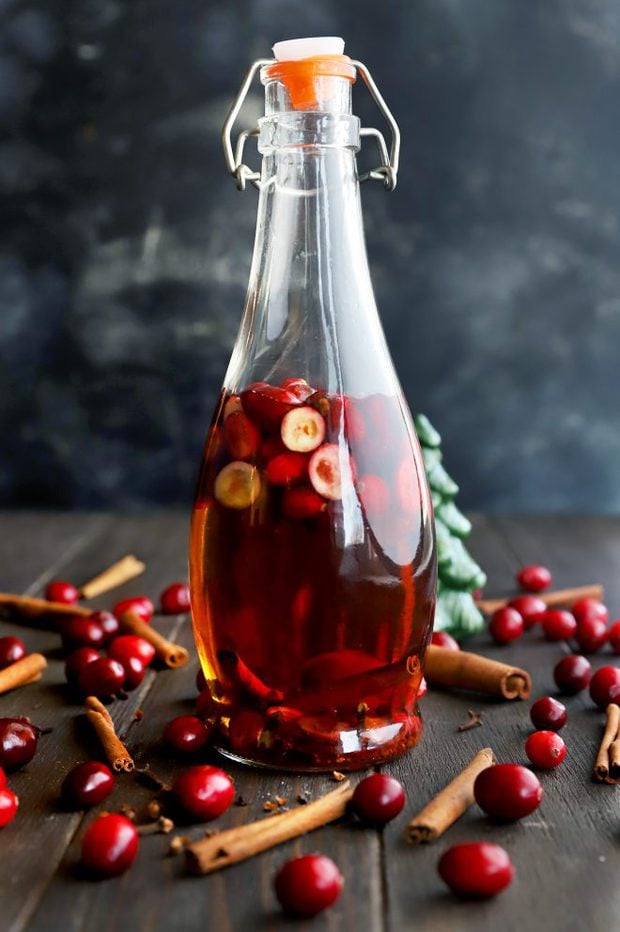 Image of infused whiskey in a bottle with cranberries and cinnamon