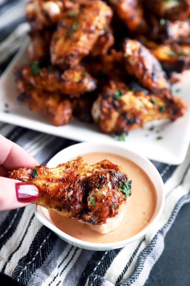 Dry rub chicken wing being dipped in sauce