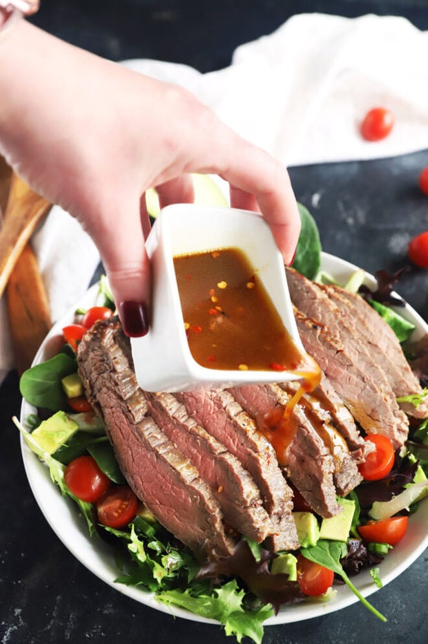 Pouring dressing over steak salad photo