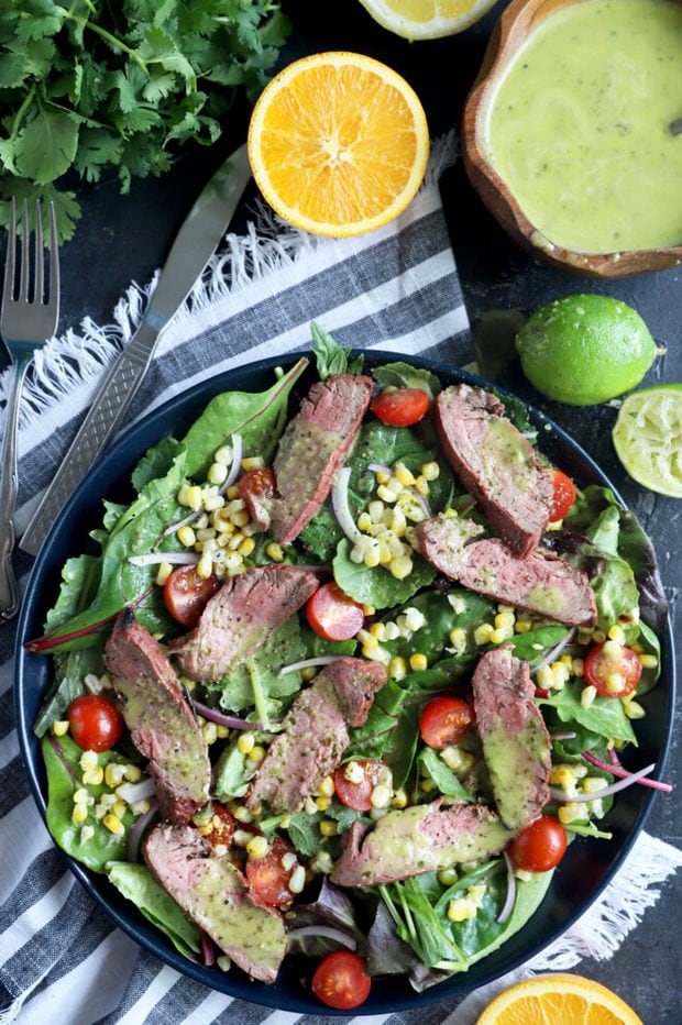 Photo of mojo steak on greens with corn